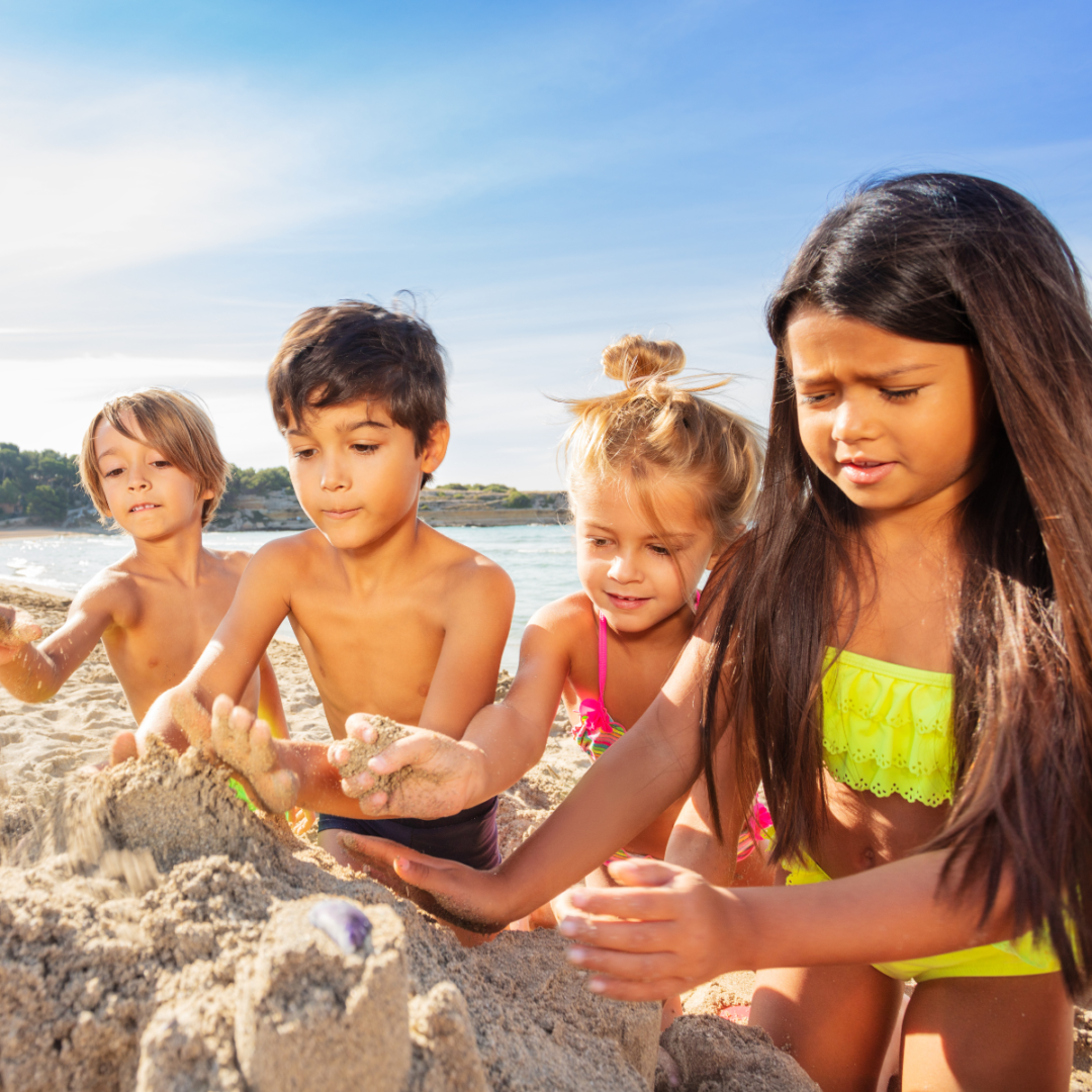 4 crianças fazendo castelinho de areia na praia